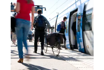 Cycliste homme de dos sur le quai d'une gare avec un train à l'arrêt