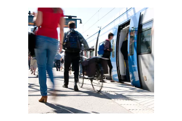 Cycliste homme de dos sur le quai d'une gare avec un train à l'arrêt