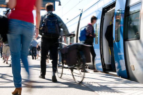 Cycliste homme de dos sur le quai d'une gare avec un train à l'arrêt