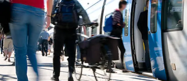 Cycliste homme de dos sur le quai d'une gare avec un train à l'arrêt